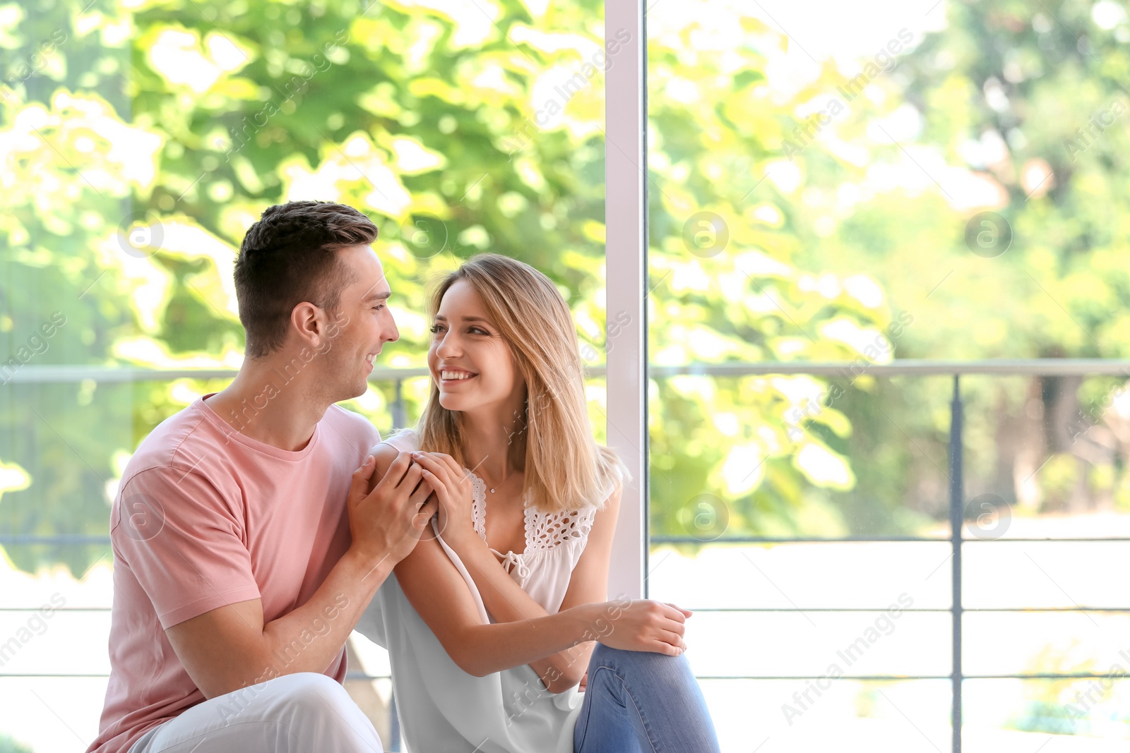 Photo of Happy young couple sitting near window at home