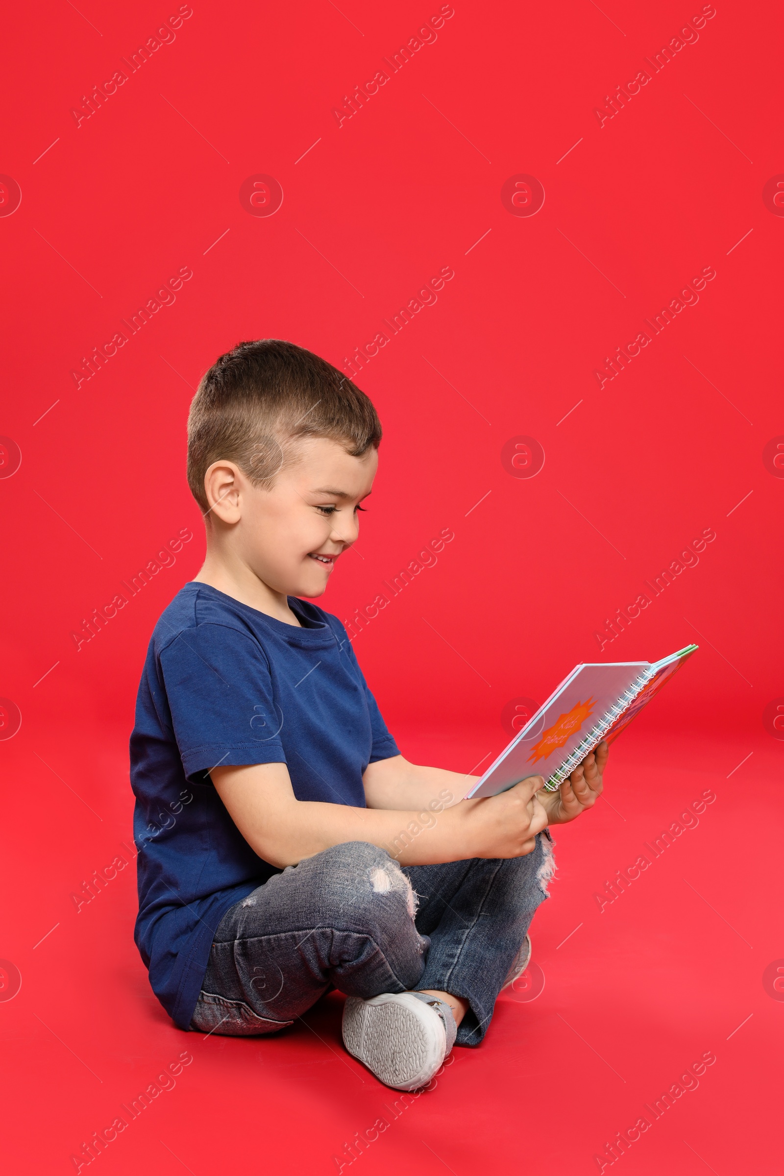 Photo of Cute little boy reading book on color background, space for text