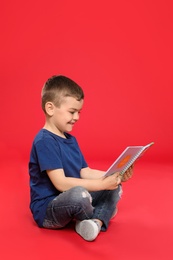 Cute little boy reading book on color background, space for text