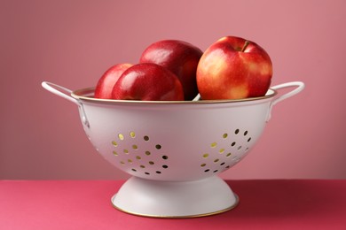 Photo of Colander with fresh apples on color background