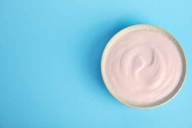 Photo of Tasty organic yogurt on light blue background, top view. Space for text