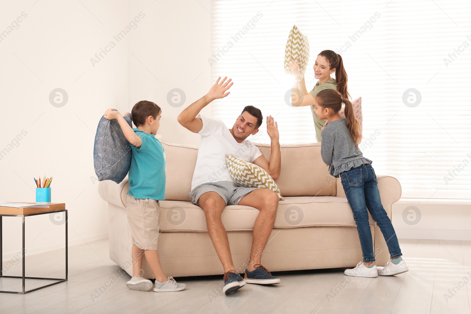 Photo of Happy family having pillow fight in living room