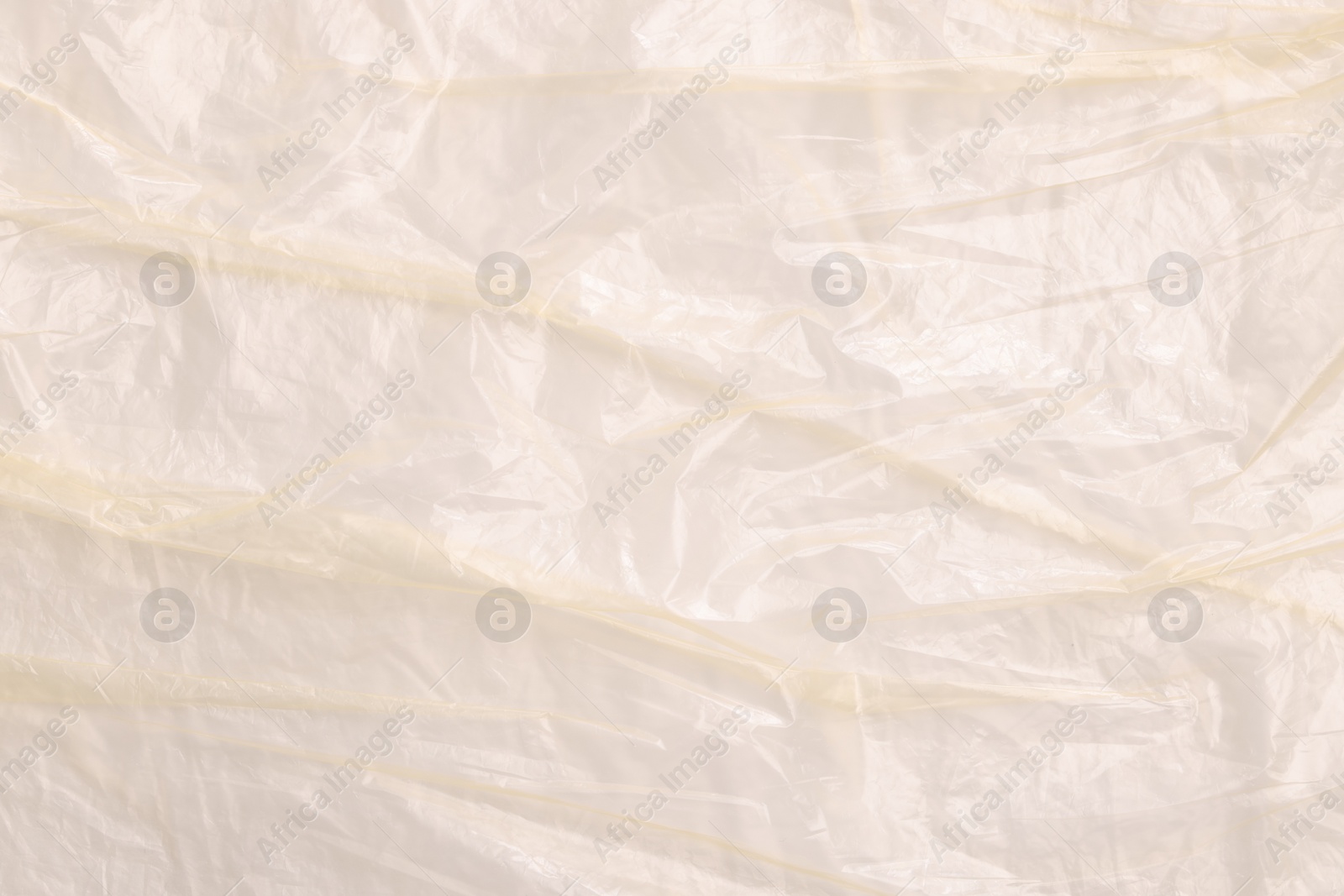 Photo of Crumpled yellow plastic bag as background, top view