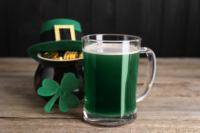 Photo of St. Patrick's day celebration. Green beer, leprechaun hat, pot of gold and decorative clover leaf on wooden table
