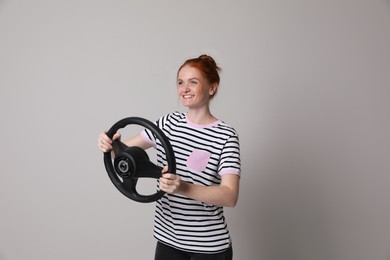 Photo of Happy young woman with steering wheel on grey background