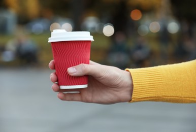 Photo of Woman holding paper takeaway cup outdoors, closeup. Coffee to go