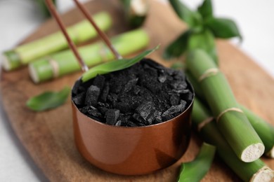 Photo of Fresh bamboo and charcoal on wooden board, closeup