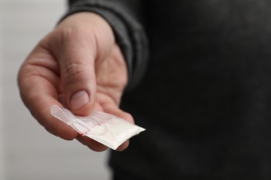 Photo of Drug addiction. Man with plastic bag of cocaine on light background, closeup