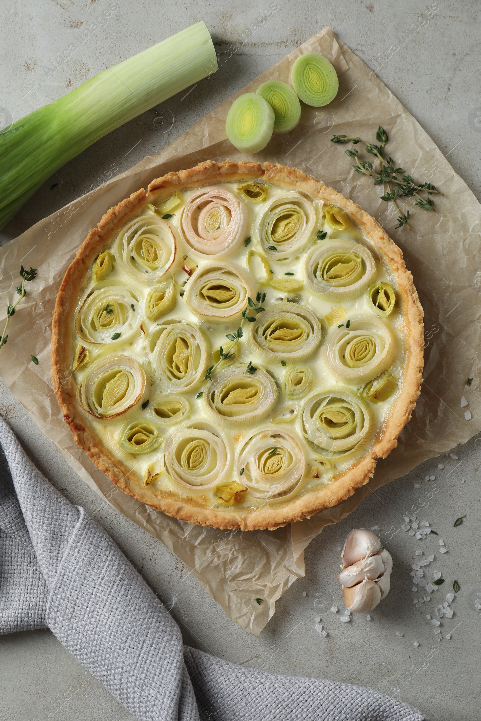 Photo of Tasty leek pie and products on grey textured table, flat lay