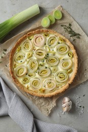 Tasty leek pie and products on grey textured table, flat lay