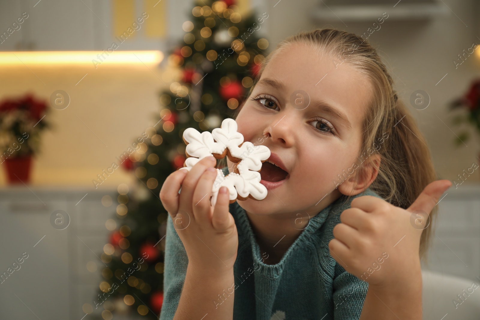 Photo of Cute little girl with Christmas gingerbread cookie at home