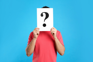 Photo of Young man with question mark sign on light blue background