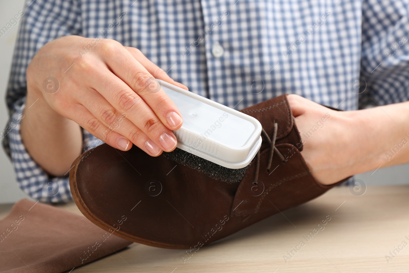 Photo of Woman taking care of stylish shoe at wooden table, closeup