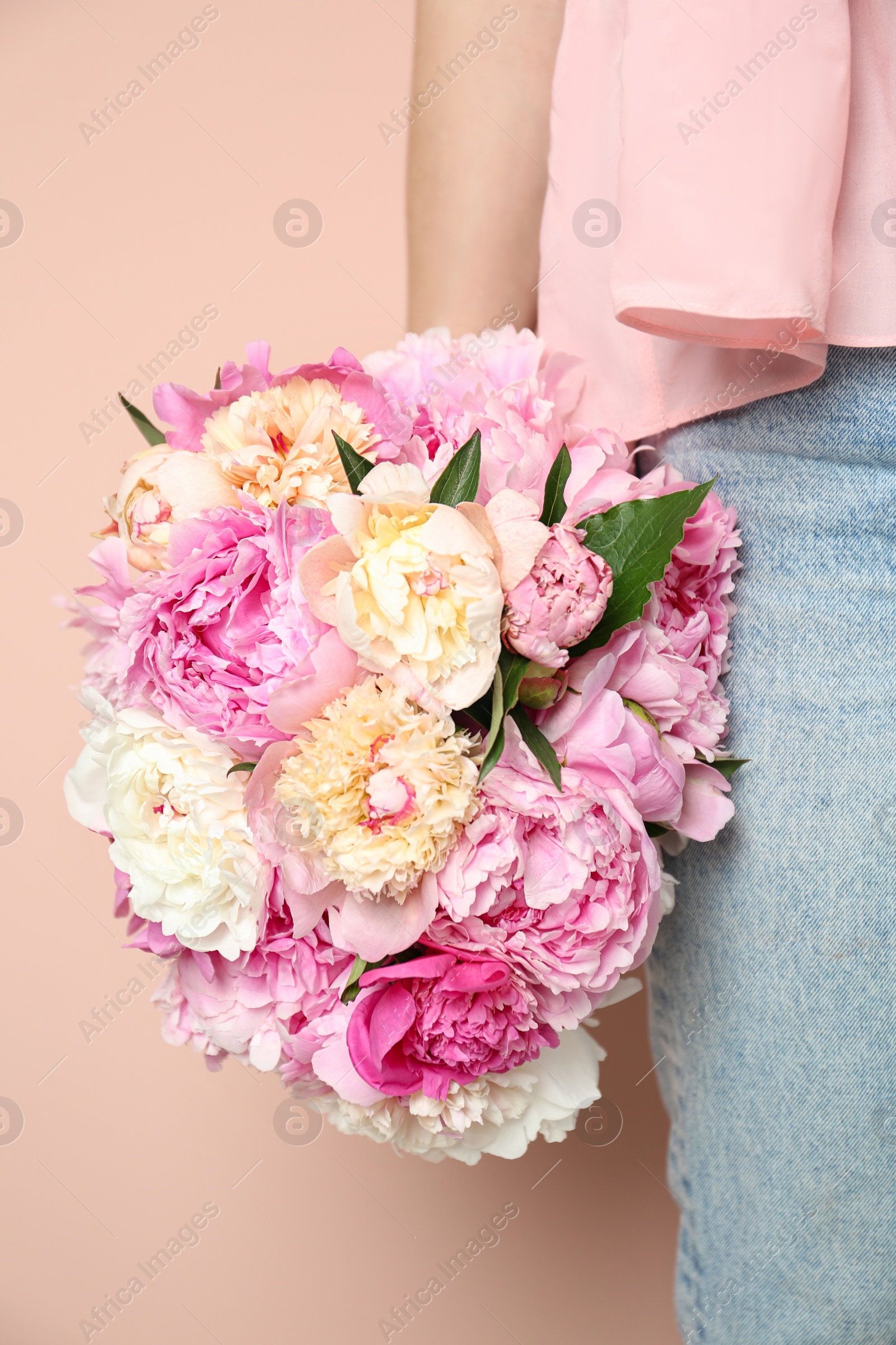 Photo of Woman with bouquet of beautiful peonies on beige background, closeup