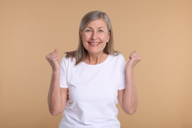 Photo of Portrait of happy surprised senior woman on beige background
