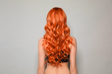 Image of Beautiful woman with long orange hair on light grey background, back view