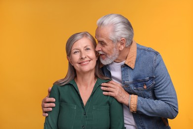 Photo of Portrait of happy affectionate senior couple on orange background