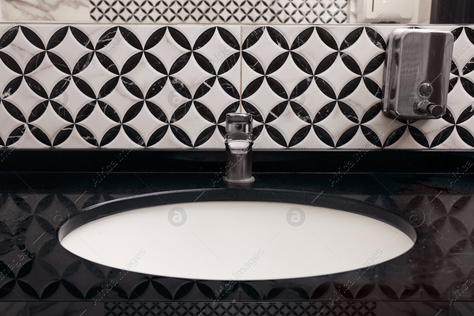 Photo of Stylish black counter with sink in public toilet