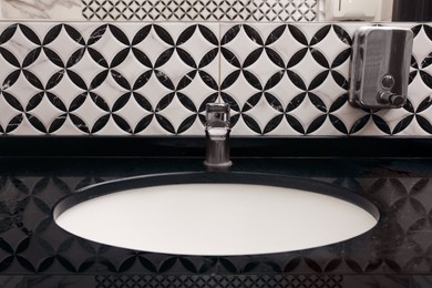 Photo of Stylish black counter with sink in public toilet