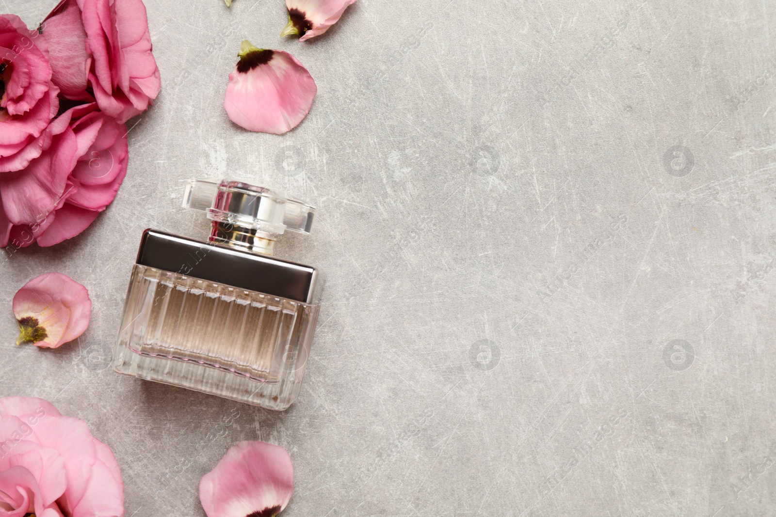 Photo of Flat lay composition with bottle of perfume and eustoma flowers on grey textured background, space for text