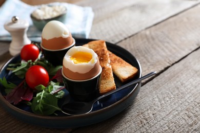 Delicious breakfast with soft boiled eggs served on wooden table, closeup