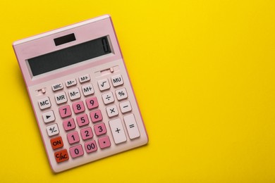 Pink calculator on yellow background, top view. Space for text