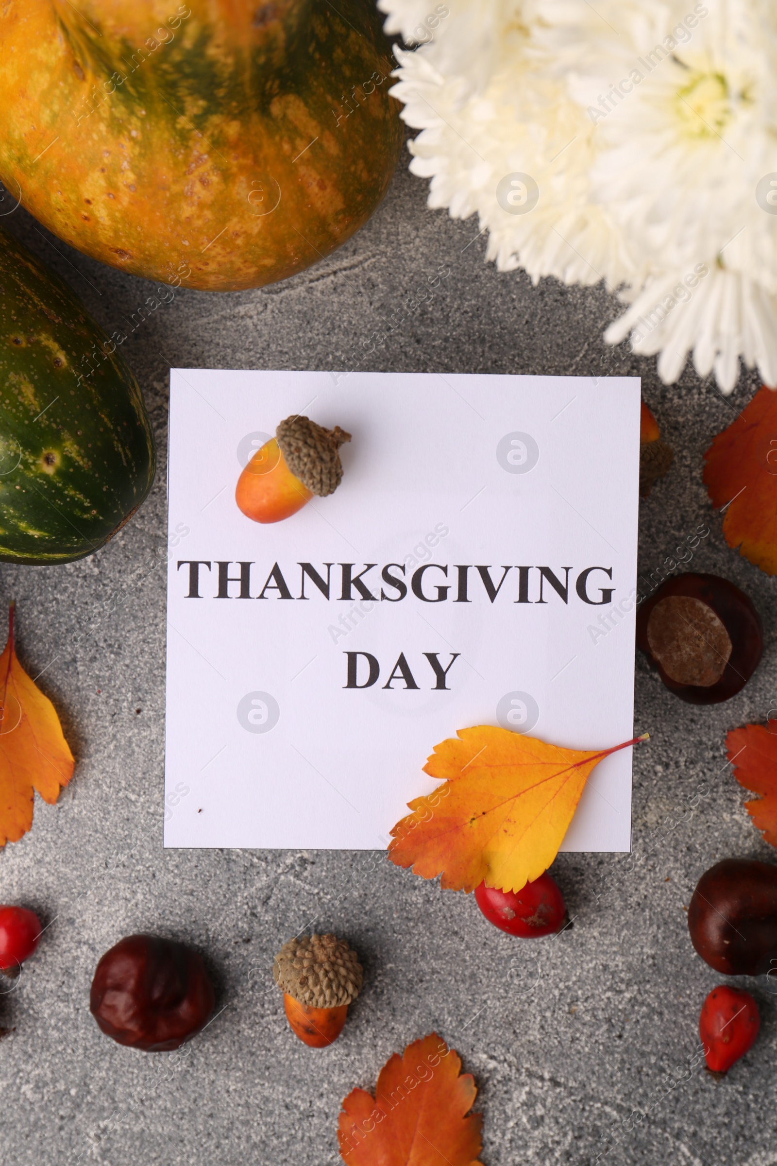 Photo of Thanksgiving day, holiday celebrated every fourth Thursday in November. Flat lay with paper card and autumn leaves on grey table