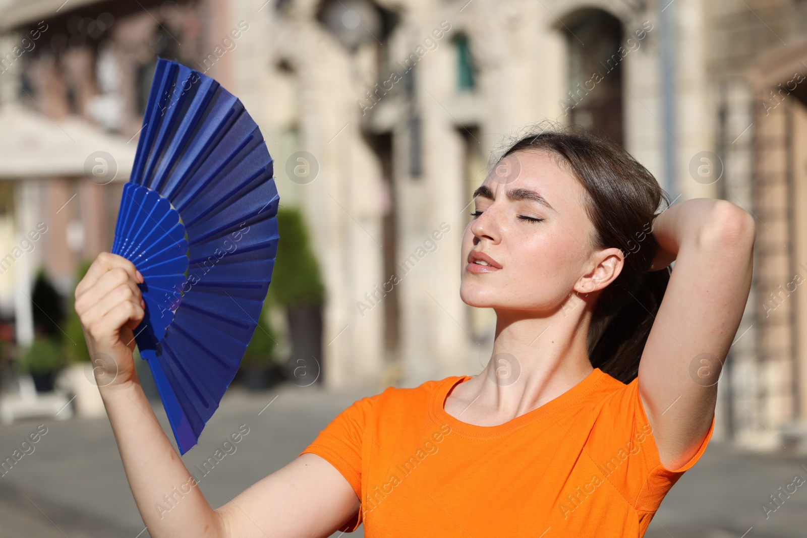 Photo of Woman with hand fan suffering from heat outdoors