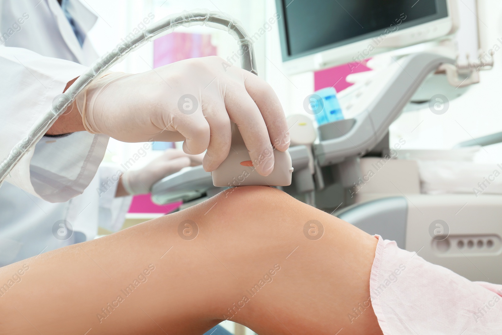 Photo of Doctor conducting ultrasound examination of knee joint in clinic, closeup