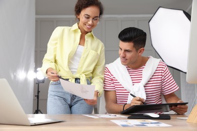 Photo of Professional retoucher with colleague working at desk in photo studio