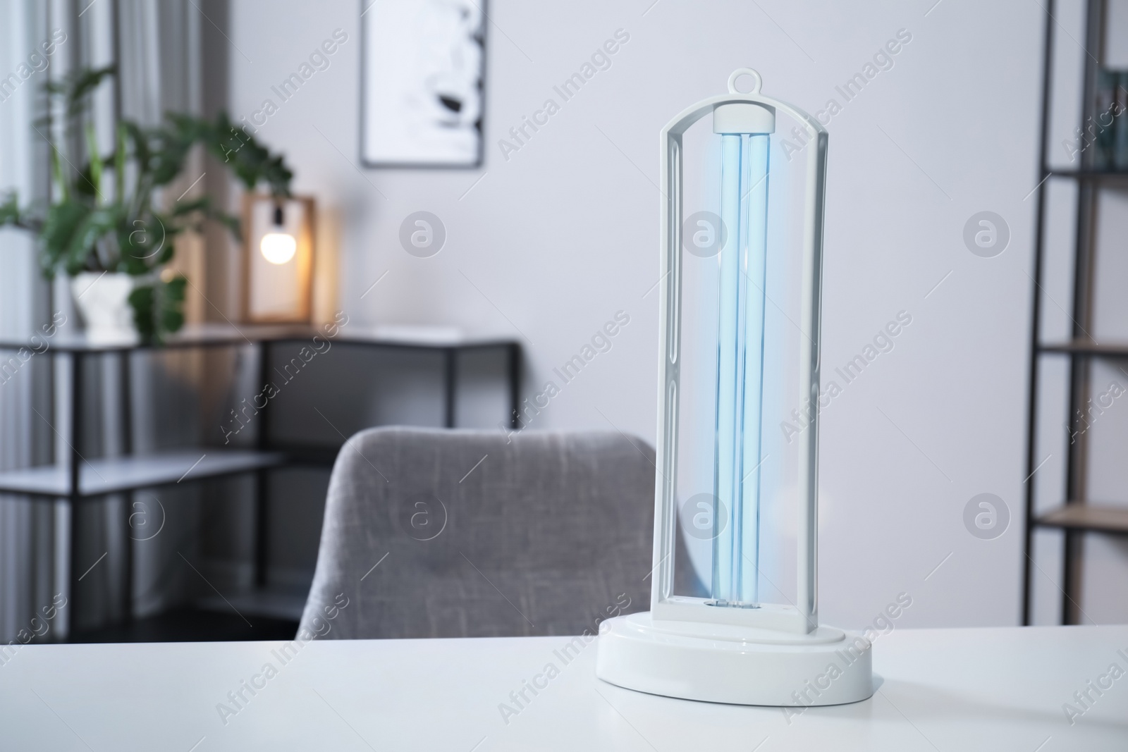 Photo of UV sterilizer lamp on table at home. Space for text