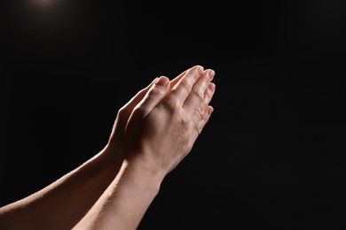 Photo of Religion. Christian woman praying on black background, closeup. Space for text