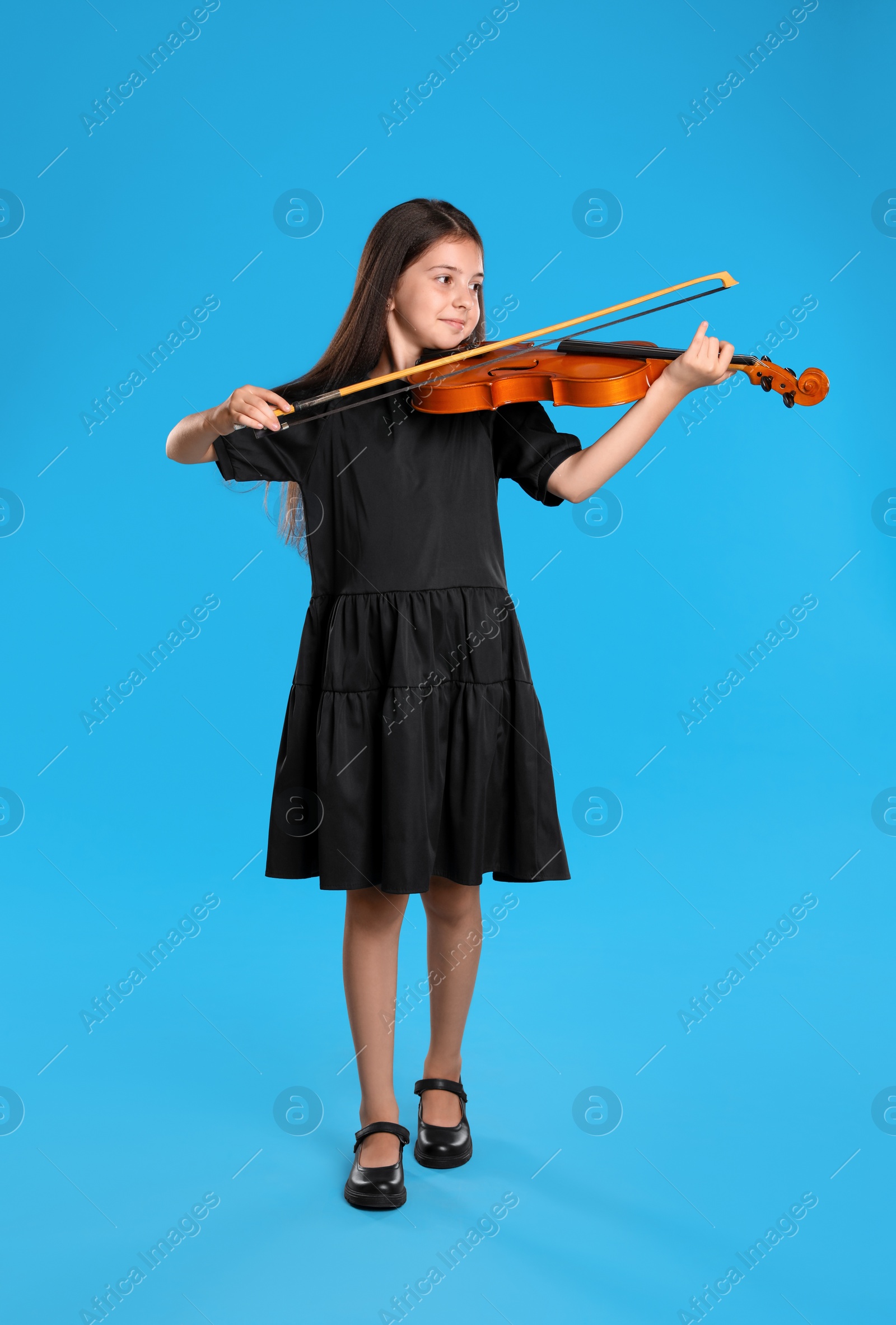 Photo of Preteen girl playing violin on light blue background