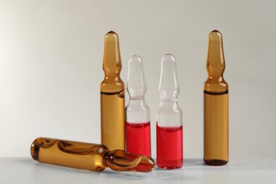 Different pharmaceutical ampoules on white table against light background