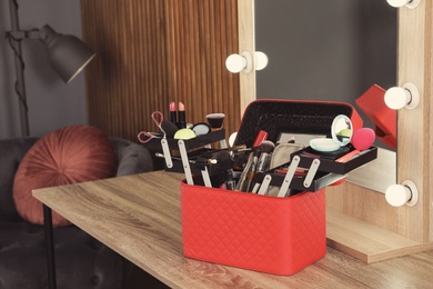 Photo of Beautician case with professional makeup products and tools on dressing table