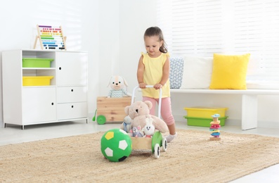 Photo of Cute little girl playing with toy walker at home