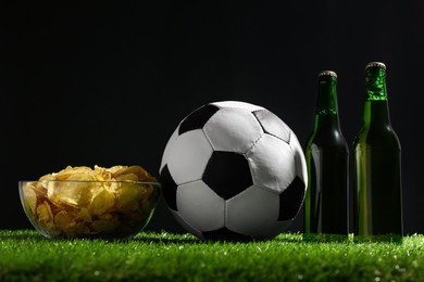 Photo of Football ball with potato chips and beer on green grass