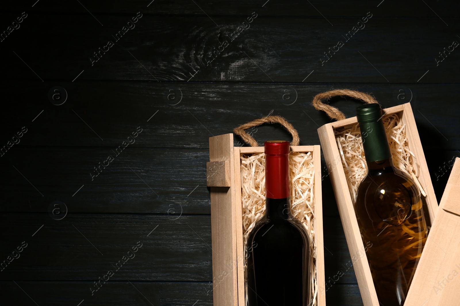 Photo of Crates with bottles of wine on wooden table, flat lay. Space for text