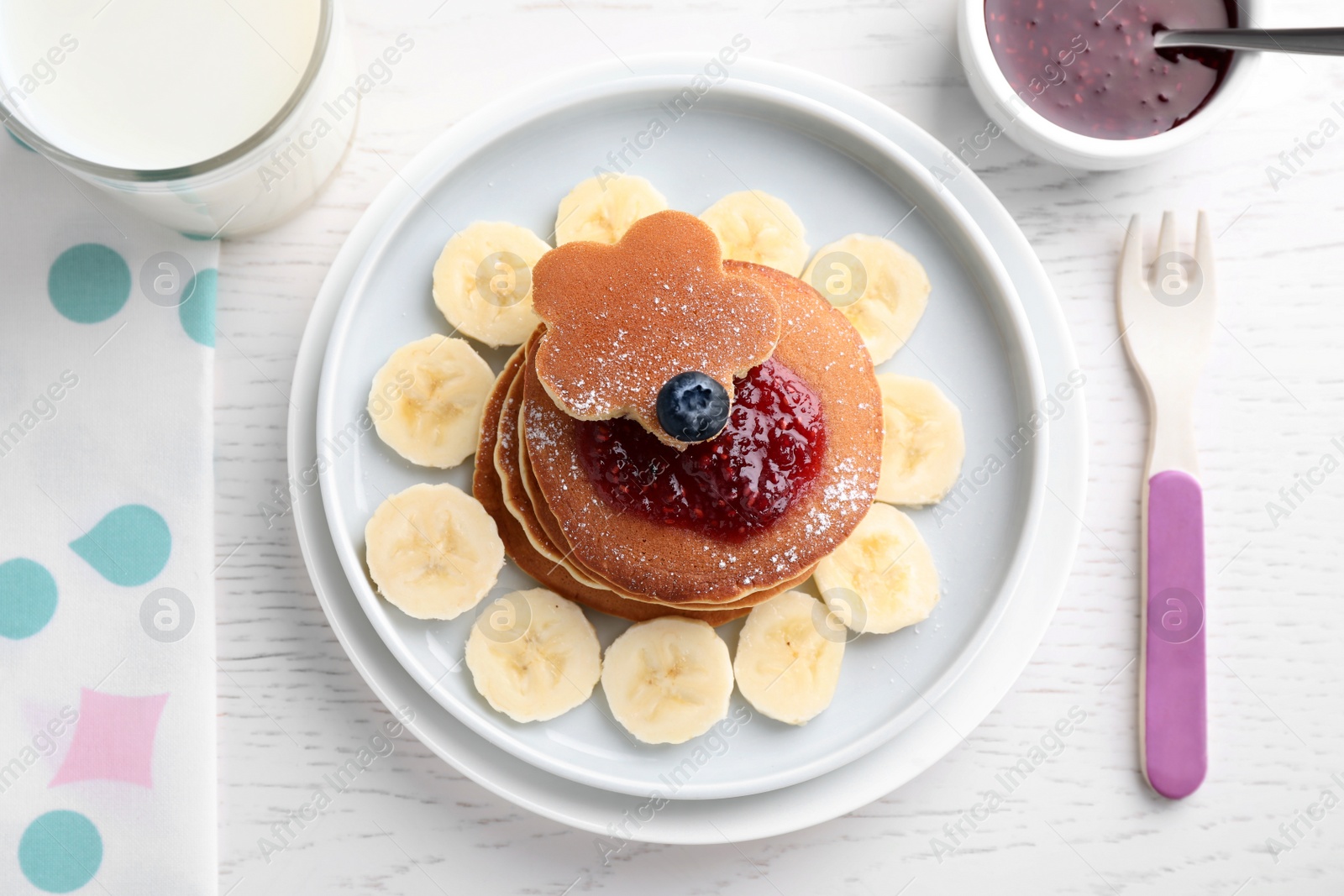 Photo of Tasty pancakes served with jam and milk on white wooden table, flat lay. Creative idea for kids breakfast