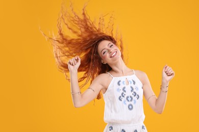 Photo of Beautiful young hippie woman dancing on orange background
