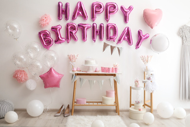 Photo of Phrase HAPPY BIRTHDAY made of pink balloon letters in decorated room