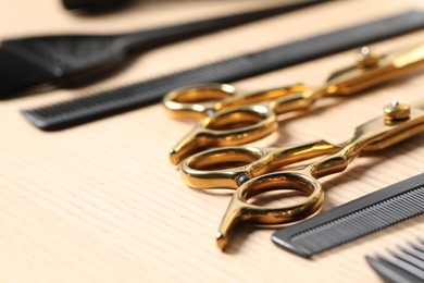 Photo of Hairdresser tools. Different scissors and combs on wooden table, closeup