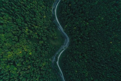 Photo of Aerial view of asphalt road surrounded by forest with beautiful green trees