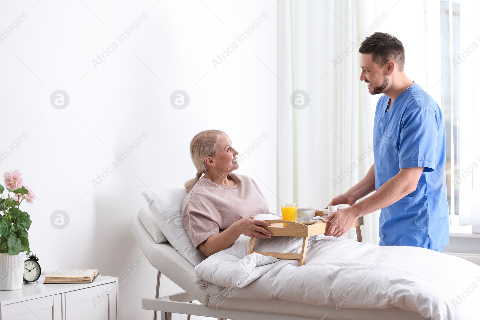 Photo of Male nurse bringing food and medicine for patient in hospital ward. Doctor's prescription