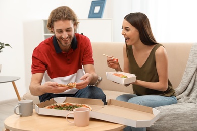 Photo of Young couple having lunch in living room. Food delivery