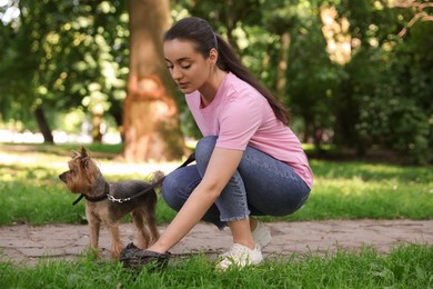 Photo of Woman picking up her dog's poop from green grass in park