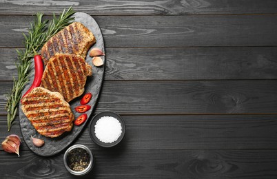 Photo of Delicious grilled pork steaks with spices on dark wooden table, flat lay. Space for text
