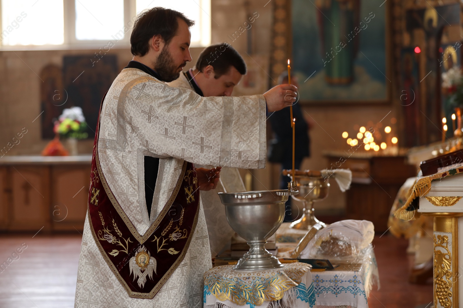 Photo of MYKOLAIV, UKRAINE - FEBRUARY 27, 2021: Deacon and priest conducting baptism ceremony in Kasperovskaya icon of Mother of God cathedral