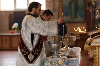 Photo of MYKOLAIV, UKRAINE - FEBRUARY 27, 2021: Deacon and priest conducting baptism ceremony in Kasperovskaya iconMother of God cathedral
