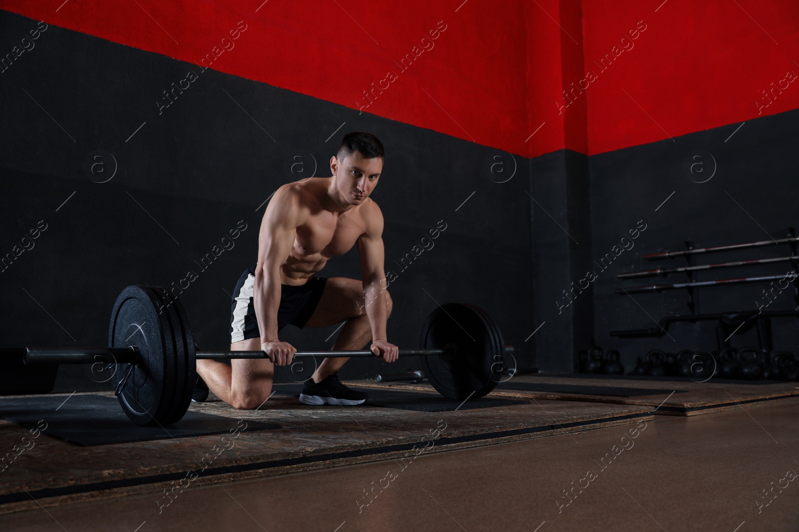Photo of Strong man lifting barbell in modern gym